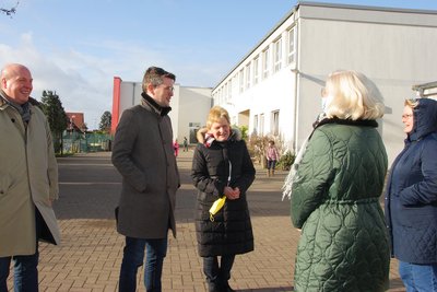 Menschengruppe im gespräch vor einer Schule 